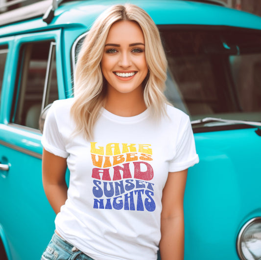 Person wearing Lake Vibes tee at lakeside during sunset